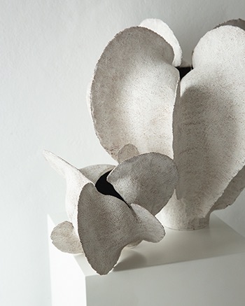 Close view of layered white ceramic petals and textured clay