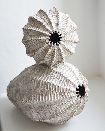 White double shell-inspired ceramic vessel with ribbed texture