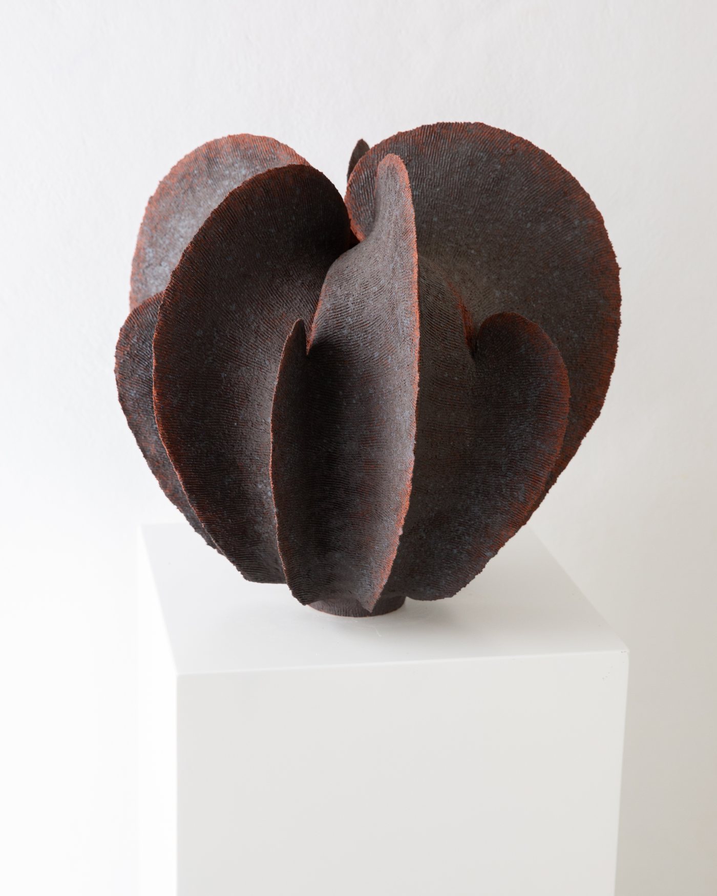Dark rust petal-like ceramic vessel with a textured surface