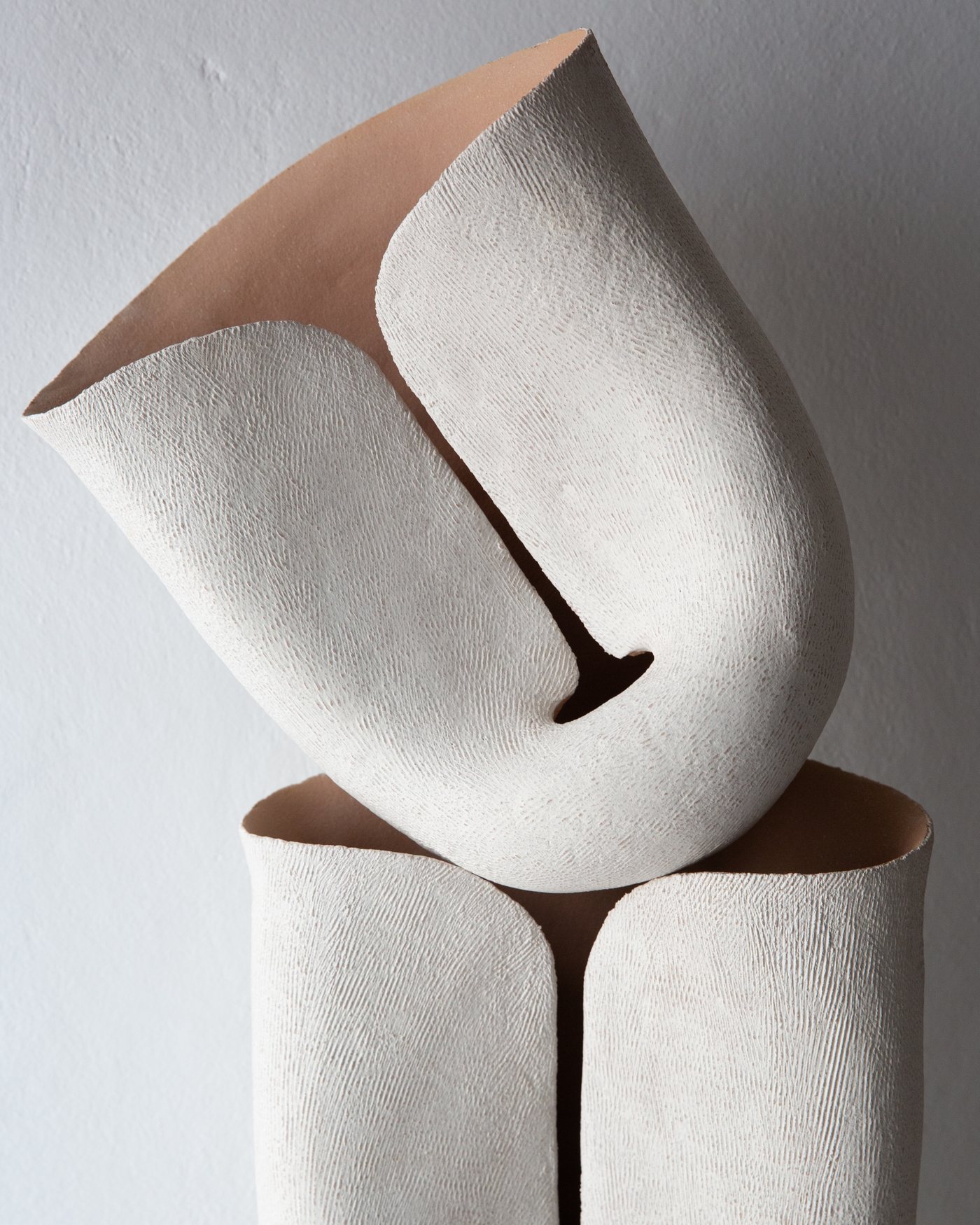 Stacked white ceramic vessels with terracotta edges and textured surfaces