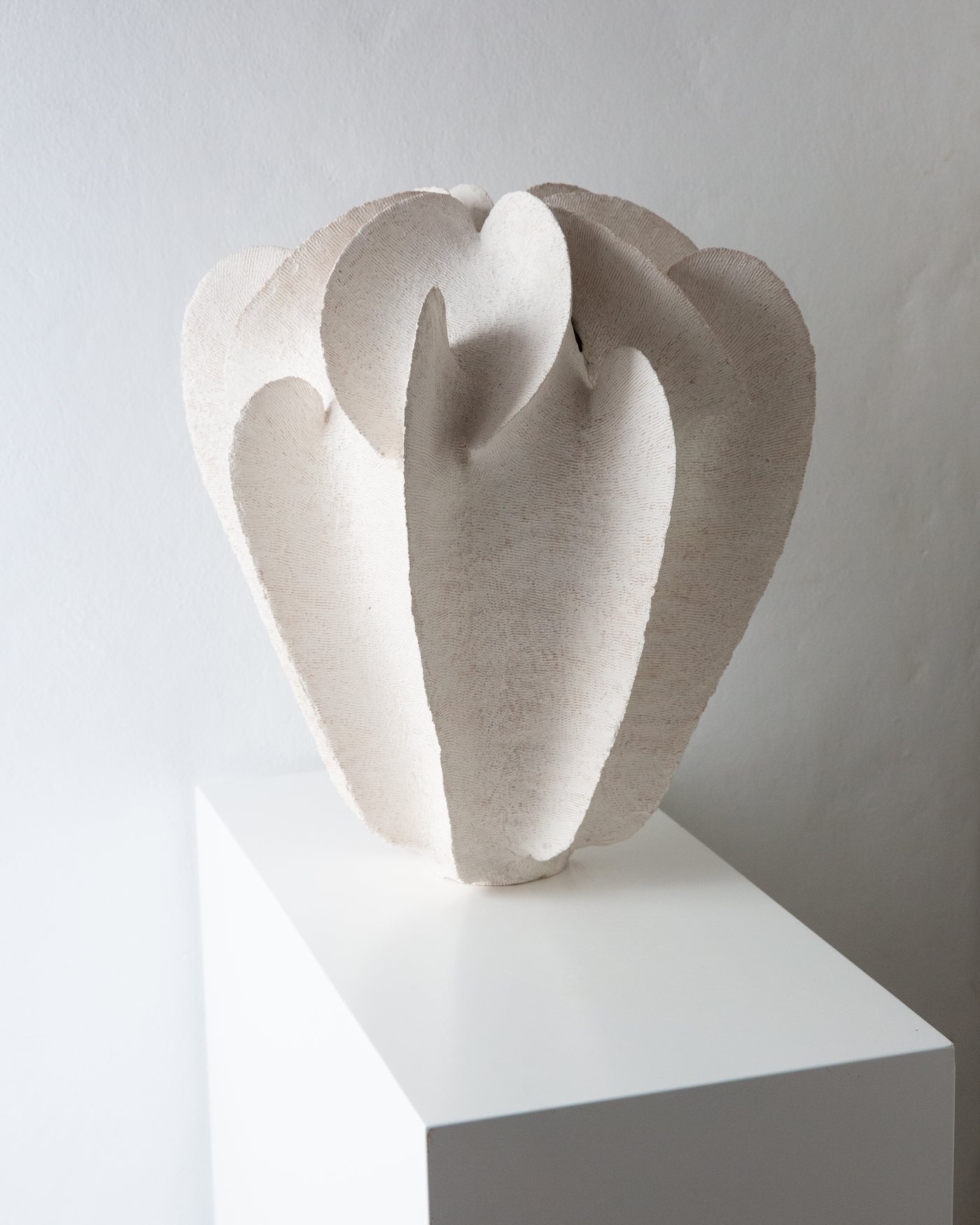 Layered white flower-like ceramic vessel on a plinth