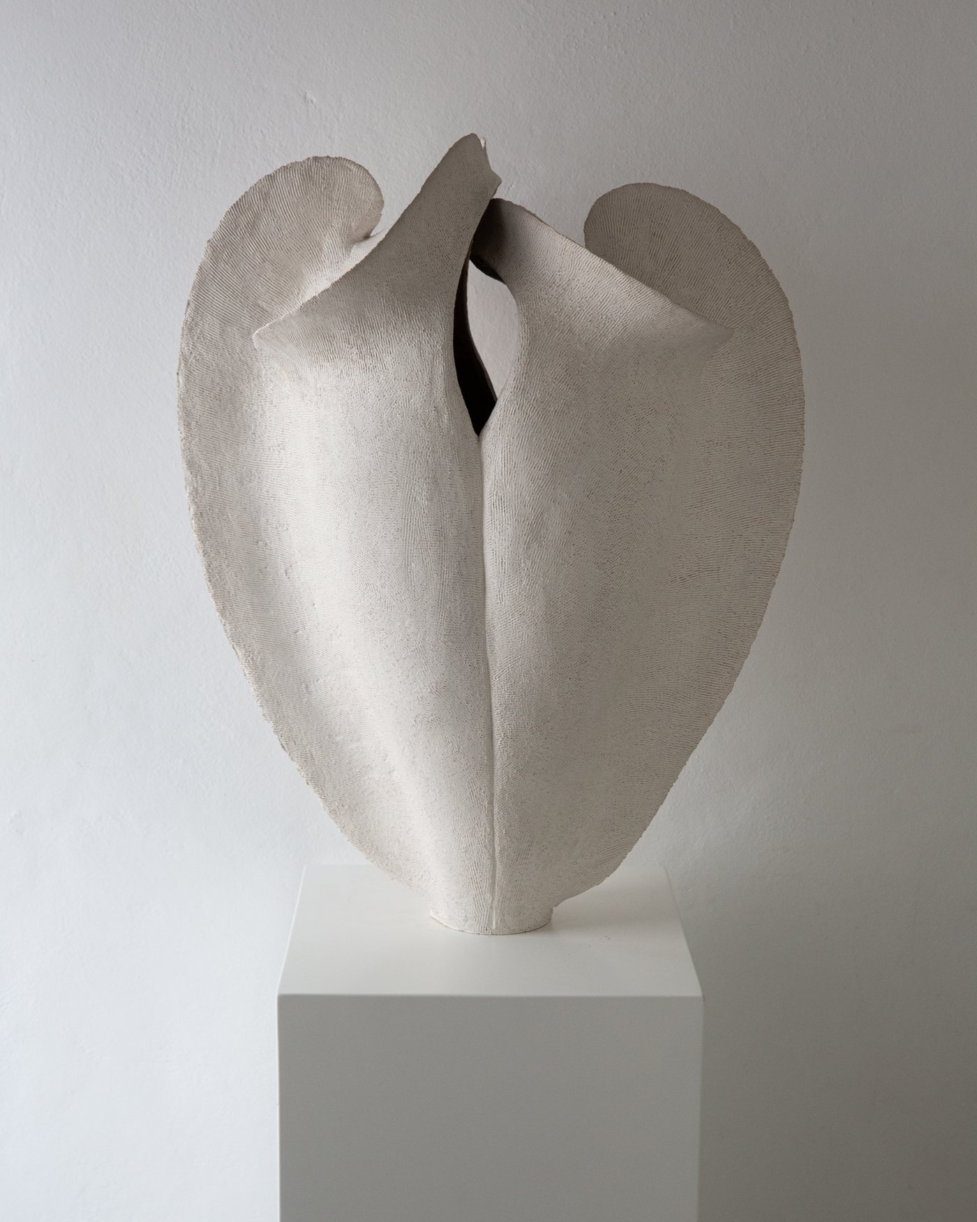 White open petal-like sculptural ceramic vessel on a plinth