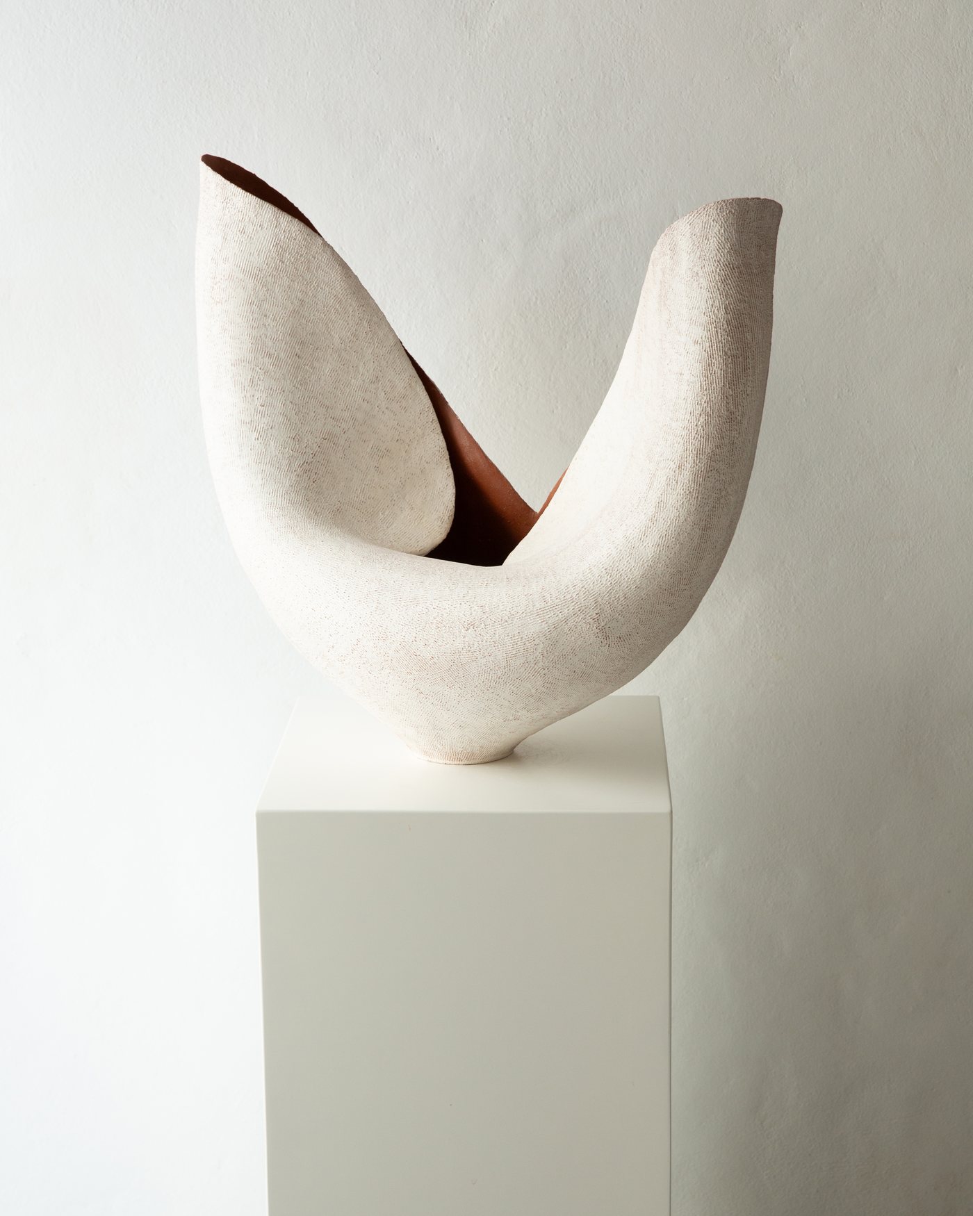 White saddle-like ceramic vessel with terracotta interior